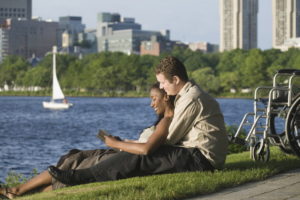 Side profile of a mid adult couple sitting in a park and reading a book.